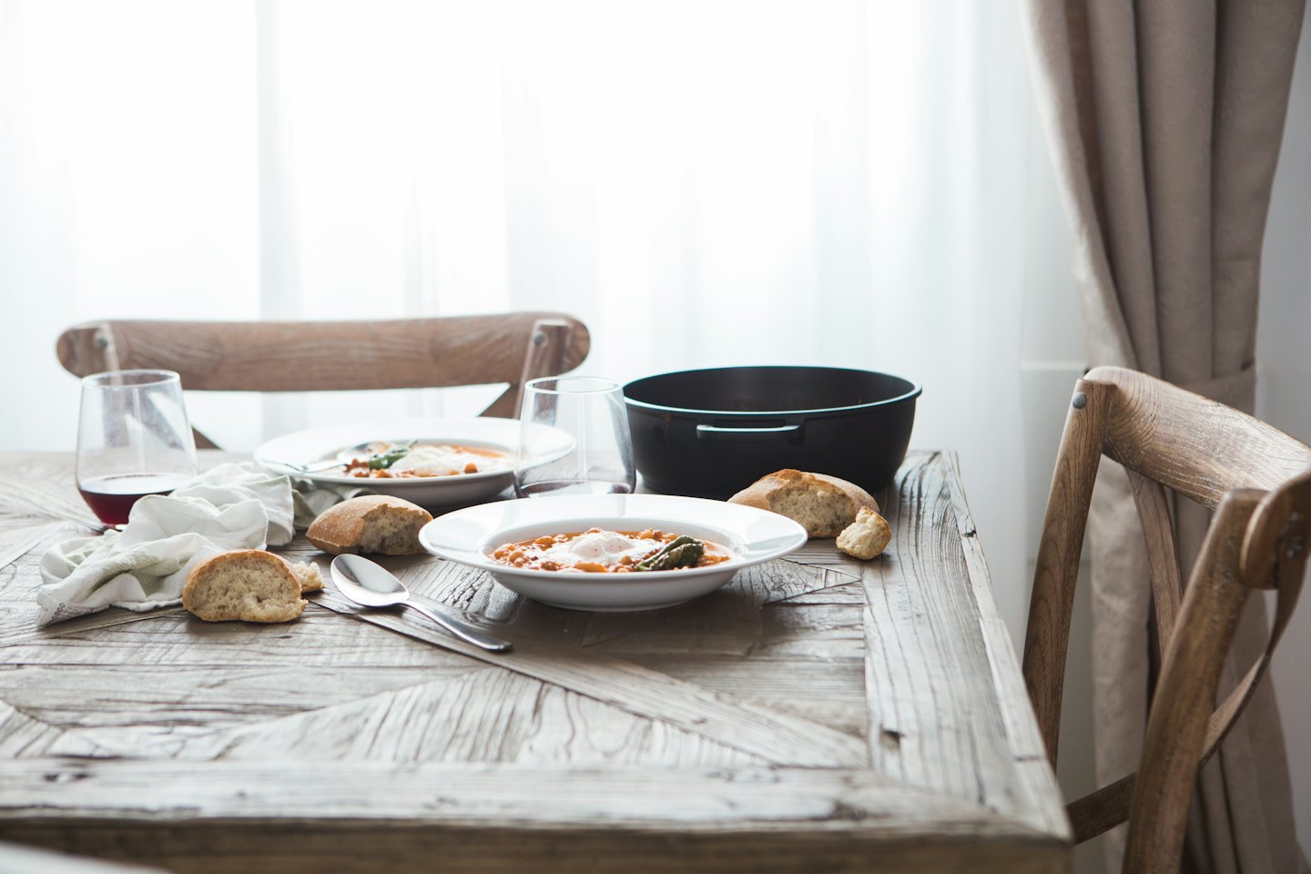 Due ciotole di sostanziosa zuppa con uova servite su un tavolo rustico.