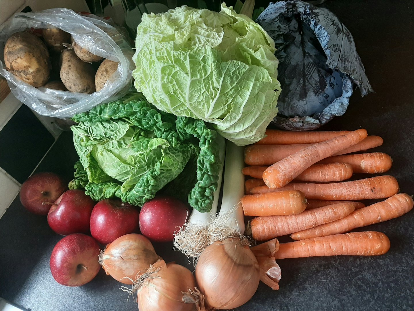 Assortimento fresco di frutta e verdura su un bancone della cucina.